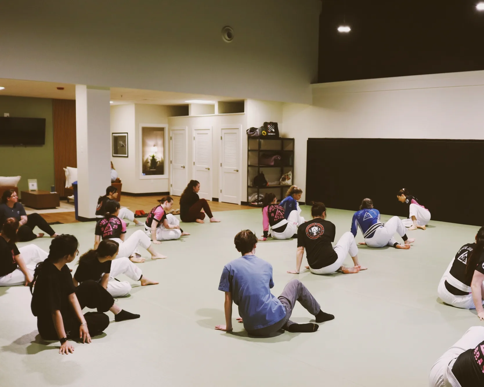 Women Empowered students seated on the mat during class in the academy's main training room.