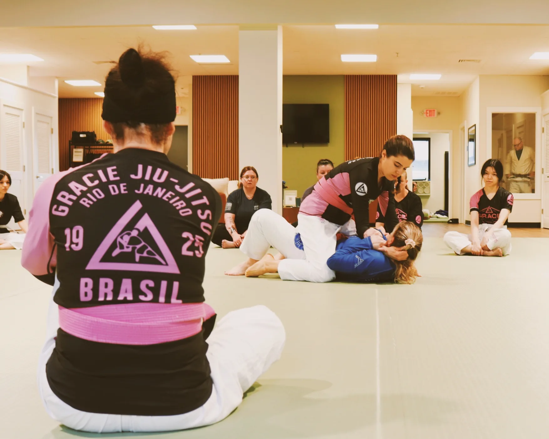 An instructor demonstrating a technique to a Women Empowered class seated in a circle.